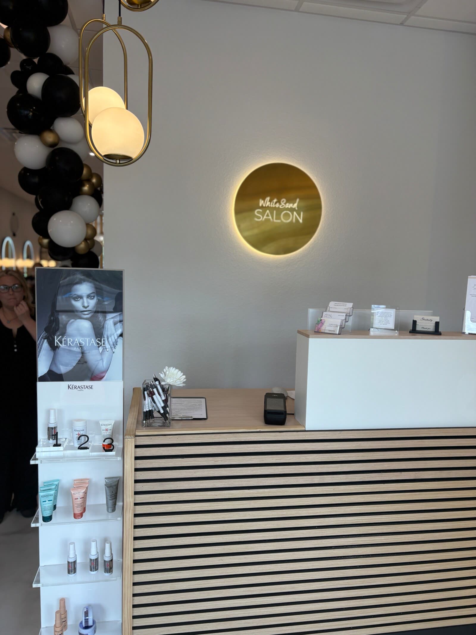 The backlit gold White Sand Salon sign above the reception desk in Clearwater