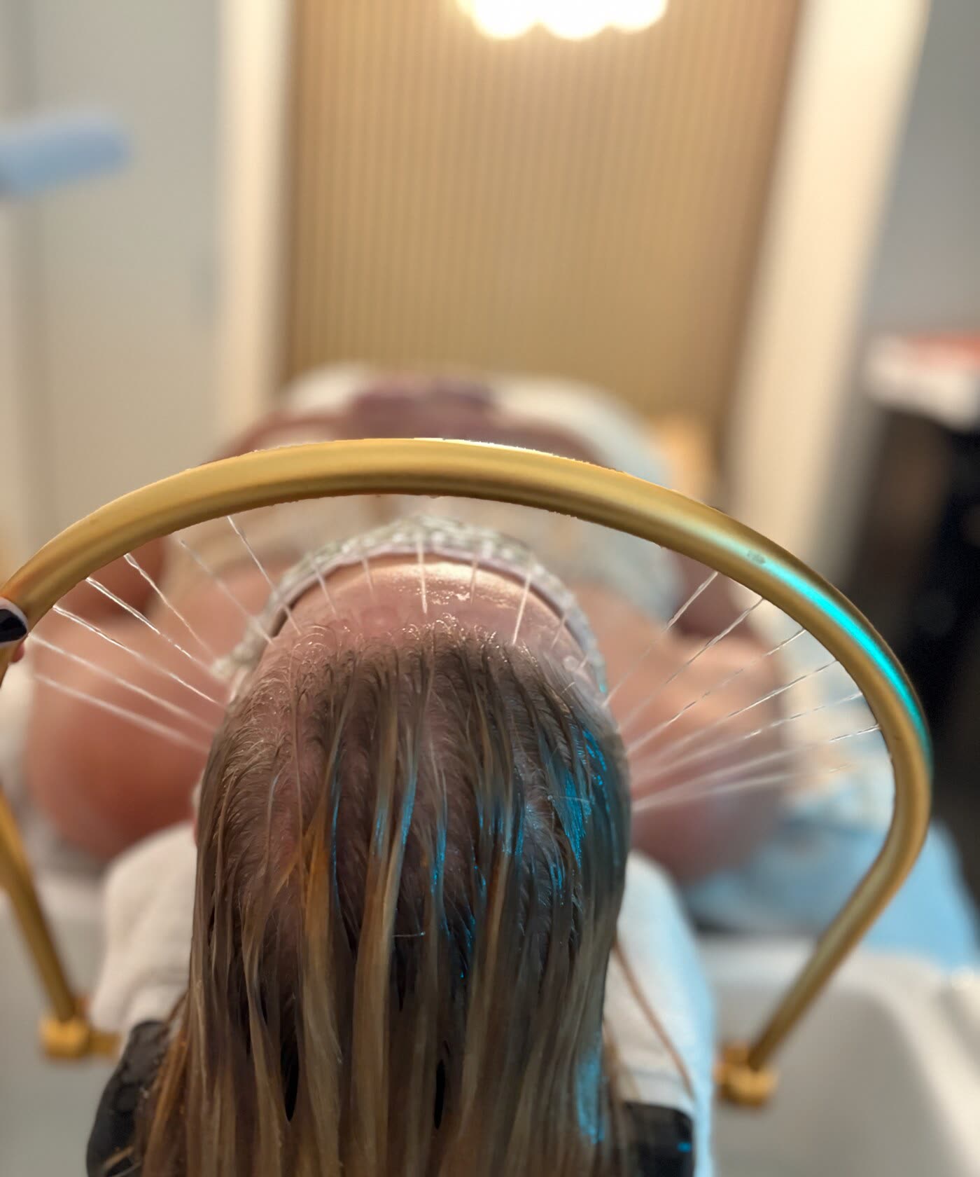 A guest under the gold scalp-treatment ring during a Japanese head spa at White Sand Salon in Clearwater