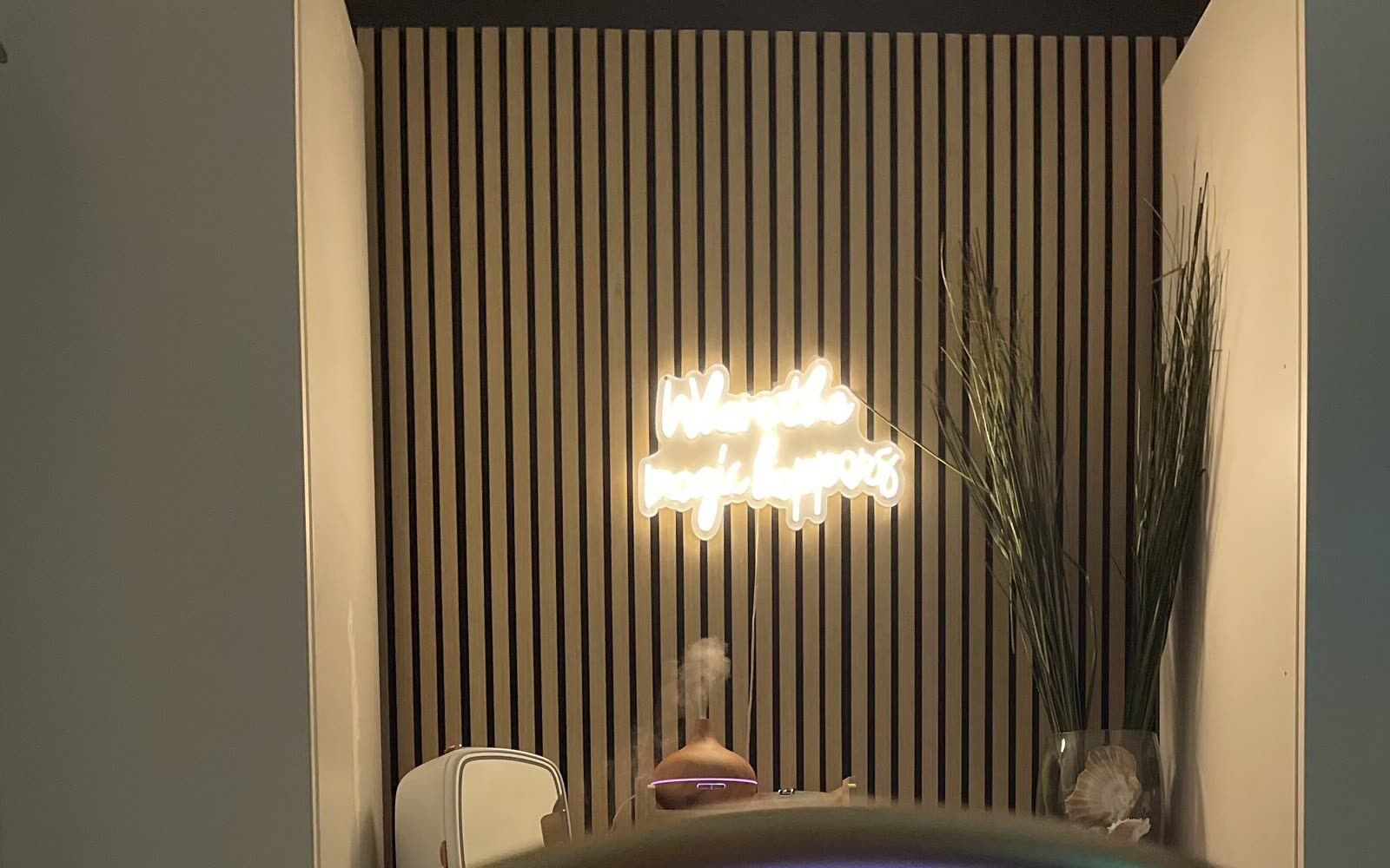 The head spa treatment room at White Sand Salon in Clearwater, its slatted wood wall and neon sign above the treatment bed