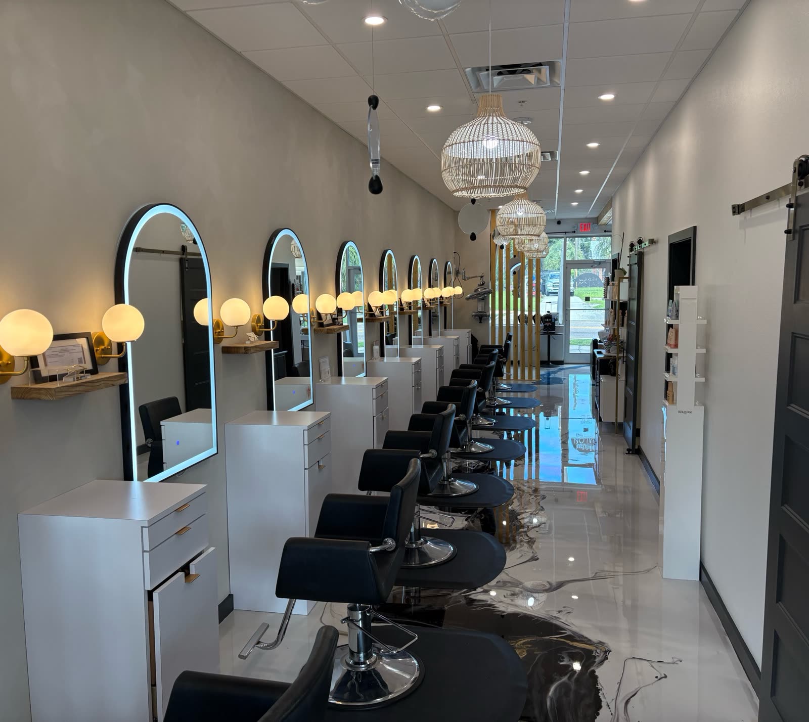The styling floor at White Sand Salon in Clearwater — arched lit mirrors, woven pendants and the row of black styling chairs